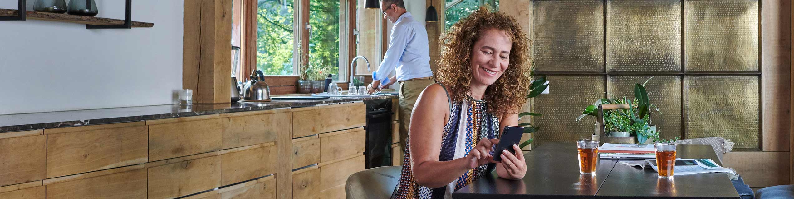 Woman sitting at the kitchen table looking at her mobile phone