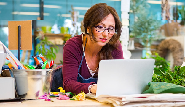 Vrouw werkt op haar laptop aan een tafel in haar eigen winkel